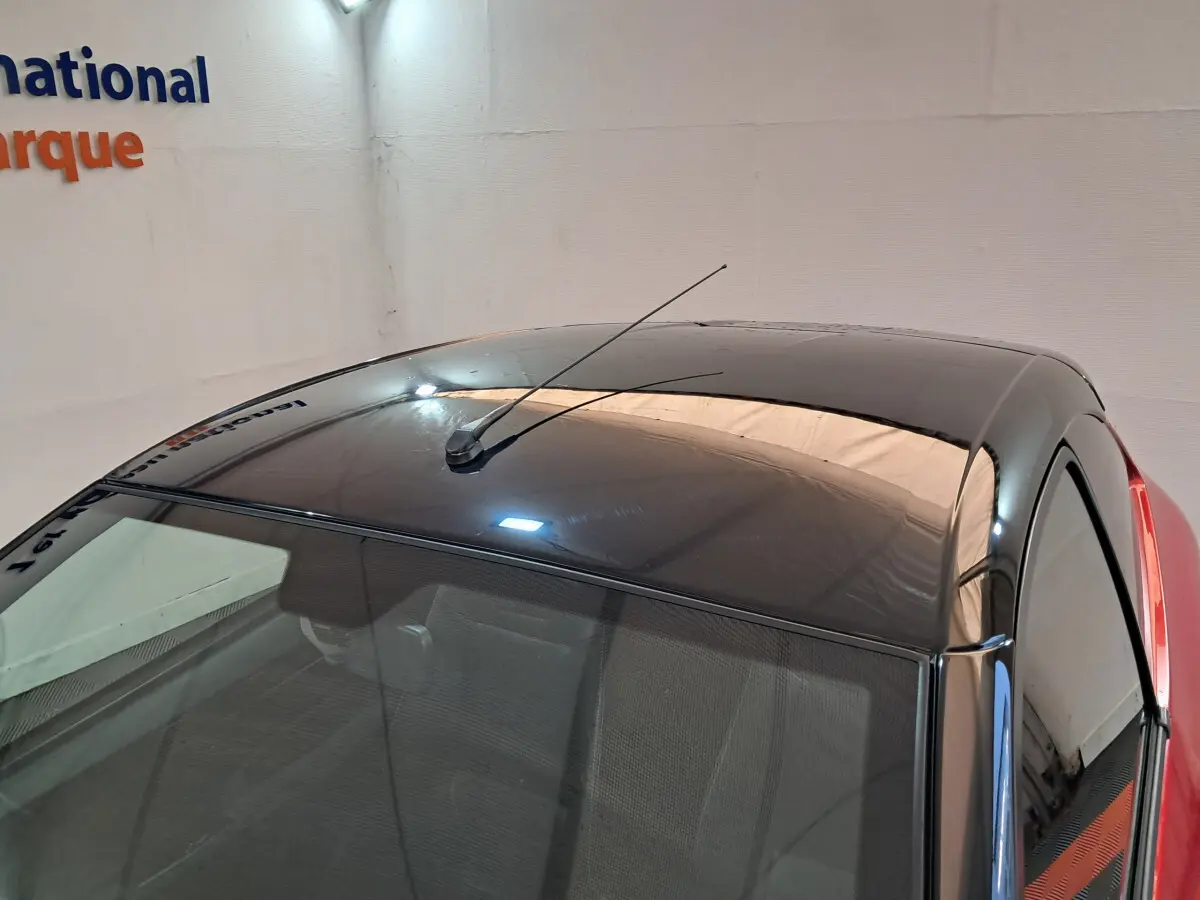 Toit noir brillant avec antenne vue en plongée sur une Aixam Ambition rouge, côté conducteur visible.