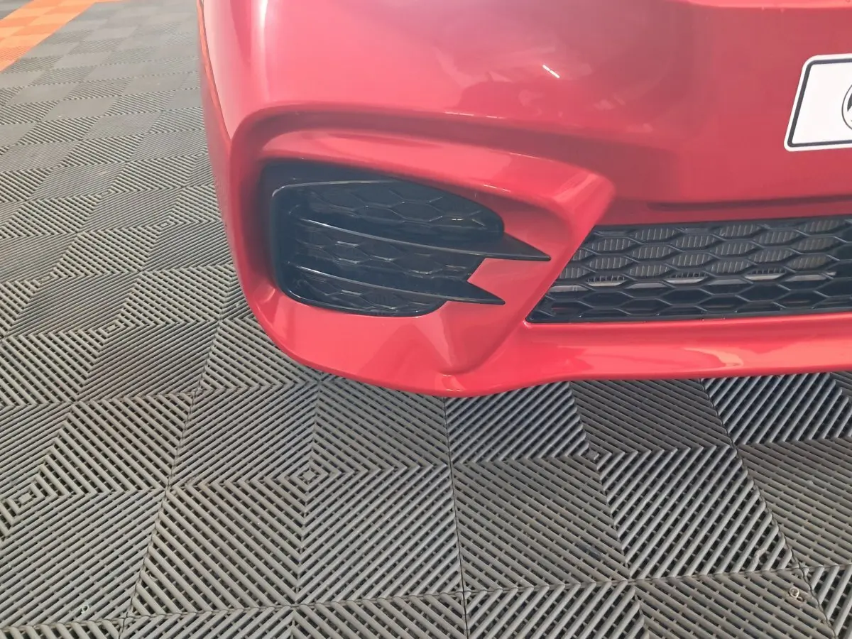 Gros plan sur l'entrée d'air avant gauche rouge de l'AIXAM AMBITION 2025 avec grille noire en nid d'abeille.