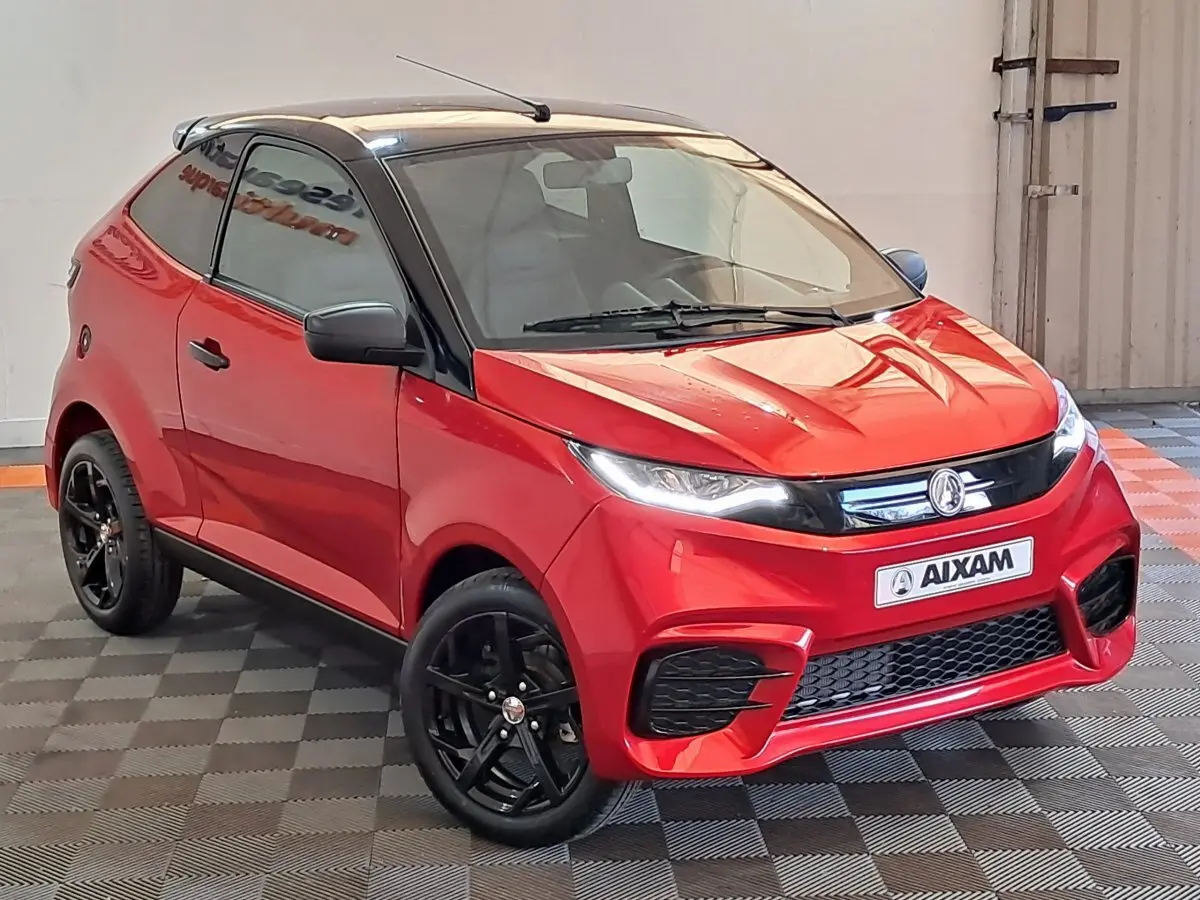 Vue 3/4 avant d'une Aixam Ambition rouge 2025 avec jantes noires et rétroviseur caméra côté gauche.