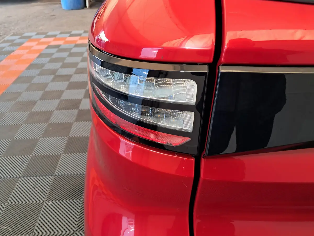 Gros plan sur le feu arrière droit rouge de l'AIXAM AMBITION 2025 avec détails noirs brillants et surface lisse.