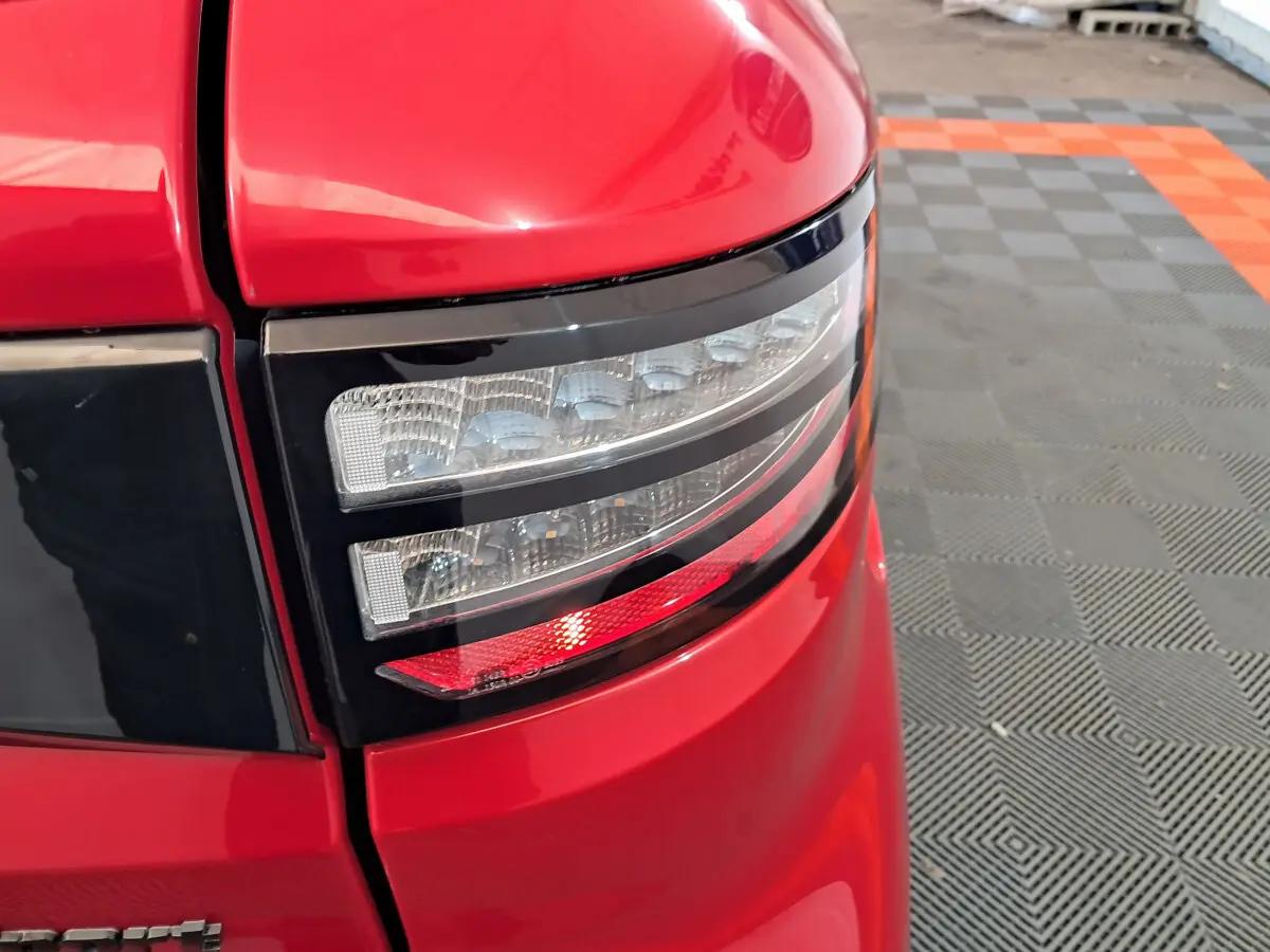 Gros plan sur le feu arrière droit rouge de l'AIXAM AMBITION 0.5 City Coupe Sport 2025 avec finition brillante.