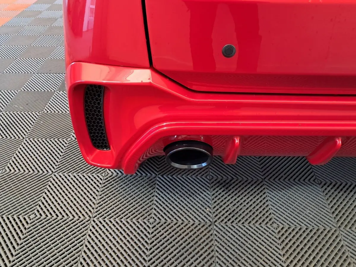 Gros plan sur l'arrière droit rouge de l'AIXAM AMBITION 2025, mettant en valeur la sortie d'échappement et le pare-chocs sport.