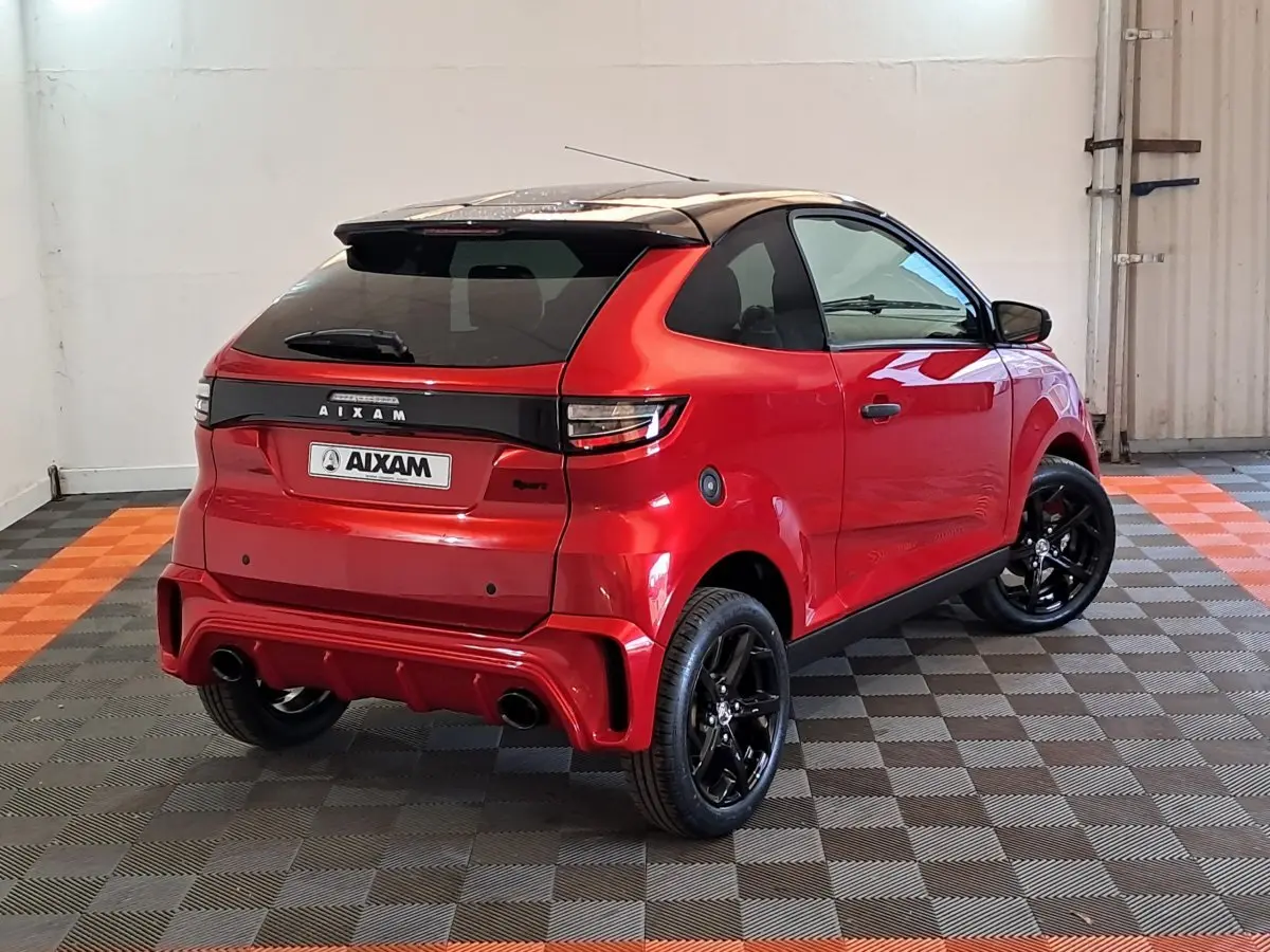 AIXAM AMBITION 2025 rouge vue 3/4 arrière droit avec jantes noires et toit noir brillant dans un garage.