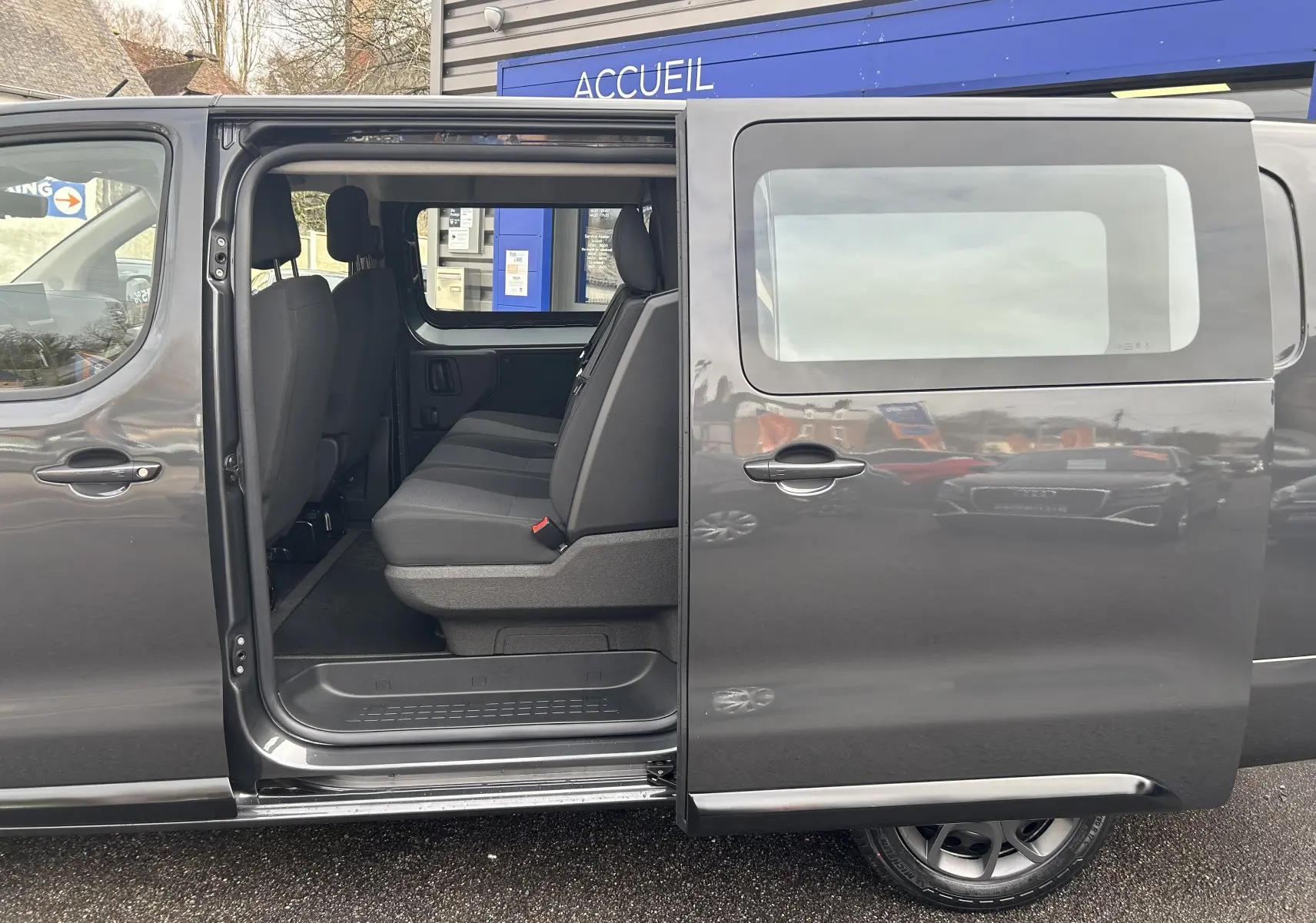 Vue latérale gauche d’un Citroën Jumpy cabine approfondie gris titane avec porte coulissante ouverte dévoilant les sièges arrière.