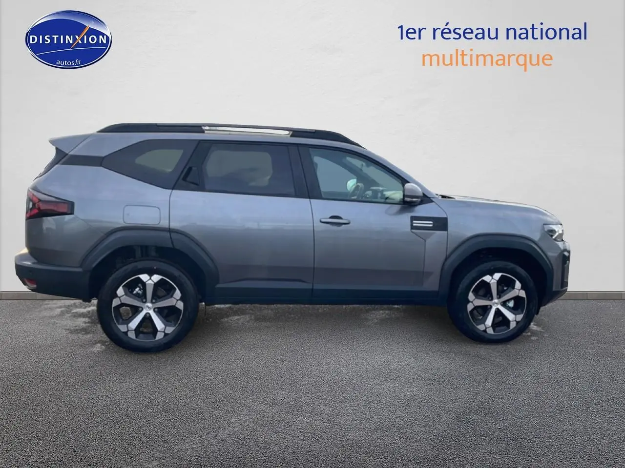 Profil droit du Dacia Bigster gris schiste 2025 avec jantes alliage diamantées et barres de toit noires.