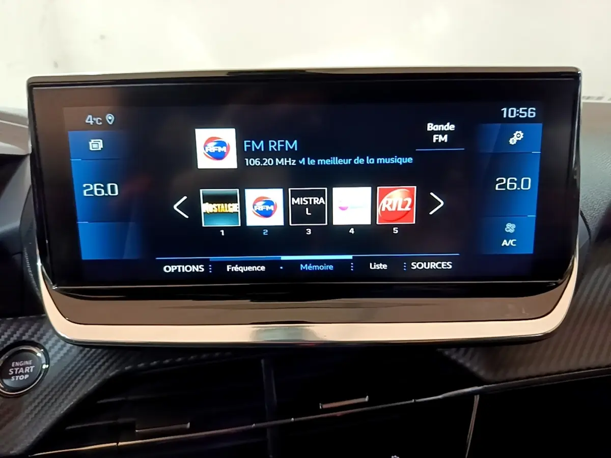 Écran tactile central de 10 pouces de la Peugeot 208 blanche, affichant la radio FM avec interface moderne.