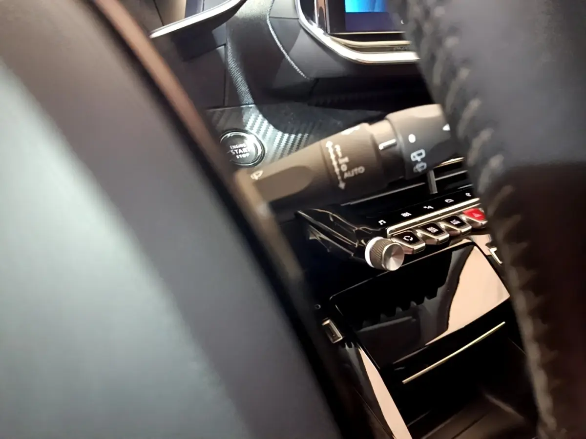 Détail intérieur du tableau de bord de la Peugeot 208 blanc, avec bouton démarrage et commandes sur la console centrale.