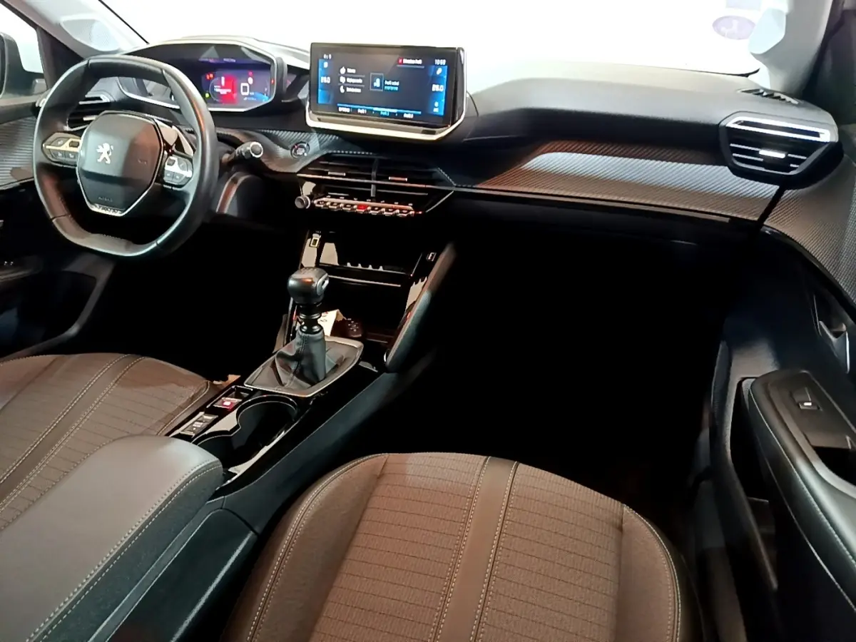 Intérieur de la Peugeot 208 PureTech 100 S&S Allure Business 2021, vue de profil droit sur tableau de bord et console centrale noire.