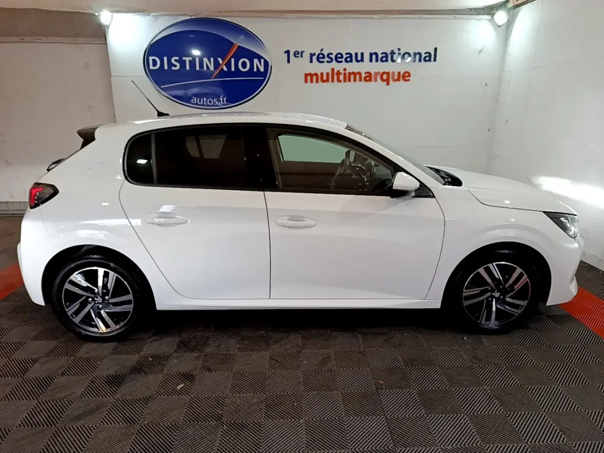 Profil droit d'une Peugeot 208 blanche PureTech 100 S&S Allure Business, roues alliage et vitres teintées visibles.