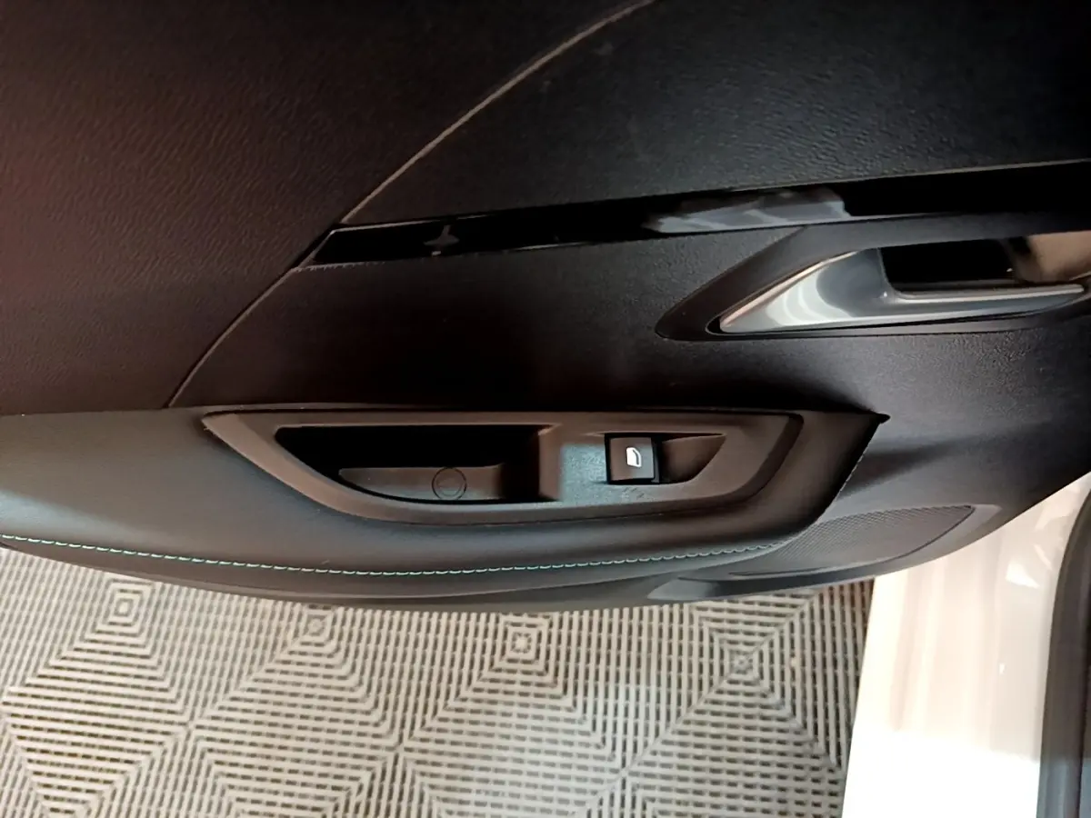 Poignée intérieure noire avec bouton de verrouillage sur la porte côté conducteur d'une Peugeot 208 blanche 2021.