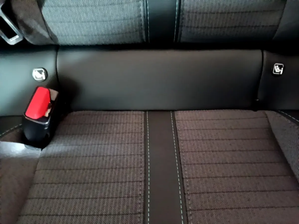 Gros plan sur la banquette arrière noire et grise de la Peugeot 208, avec ceinture de sécurité rouge visible à gauche.