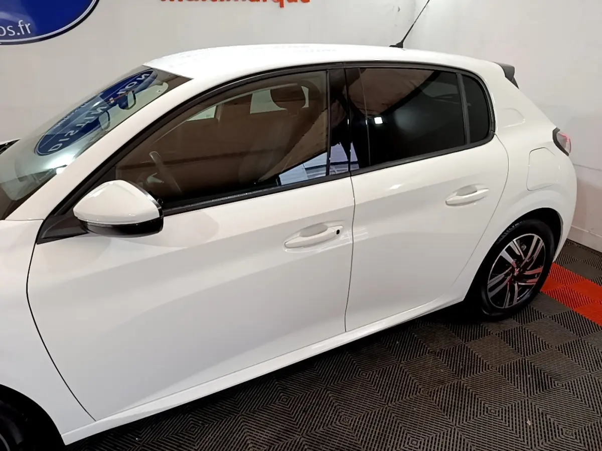 Vue de profil côté gauche d'une Peugeot 208 blanche, avec vitres teintées et jantes alliage distinctives.