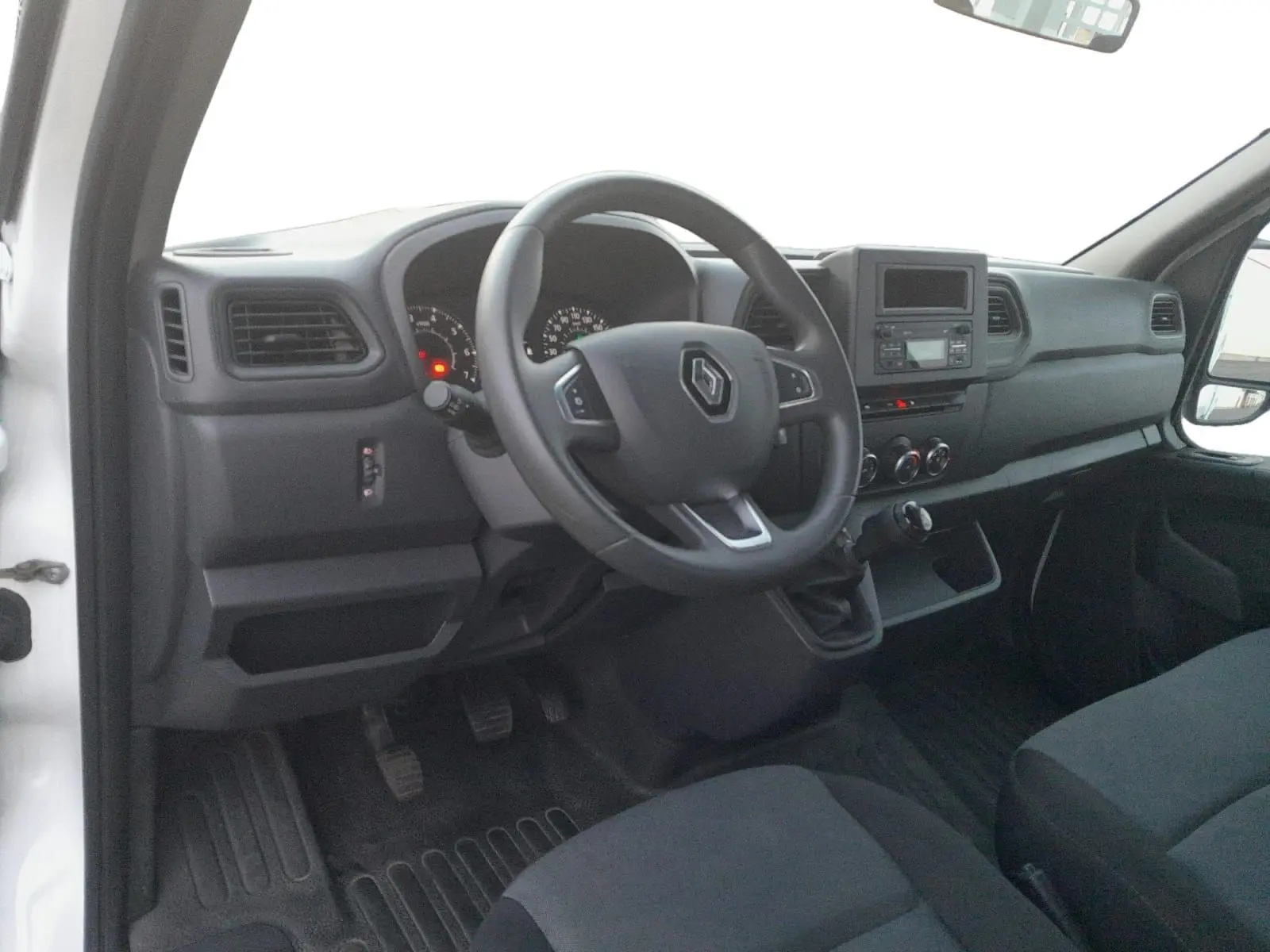 Intérieur côté conducteur du Renault Master Benne blanc 2024, tableau de bord avec volant multifonction et boîte manuelle.