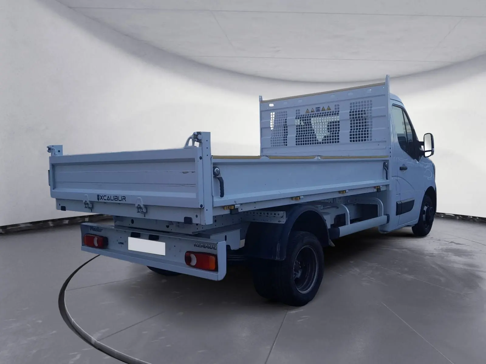 Renault Master Benne blanc vu 3/4 arrière droit avec ridelle et roues jumelées dans un studio.