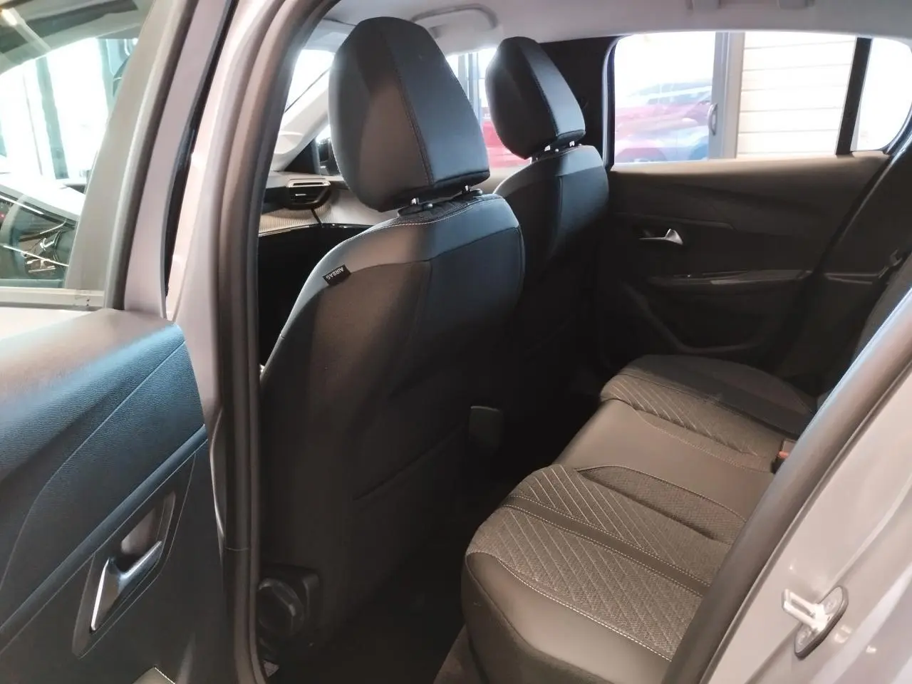 Vue intérieure arrière côté droit du Peugeot 208 2024 gris Artense, montrant les sièges arrière en tissu et cuir.