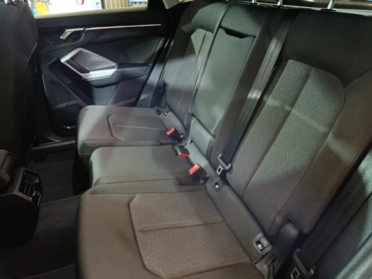 Vue intérieure côté droit des sièges arrière gris foncé de l'Audi Q3 Sportback avec ceintures et appuie-têtes visibles.