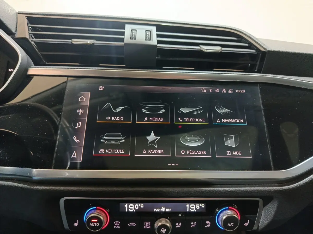 Écran tactile central de l’Audi Q3 Sportback 45 TFSI e 2021 affichant les menus multimédias et navigation, avec commandes climatisation en dessous.