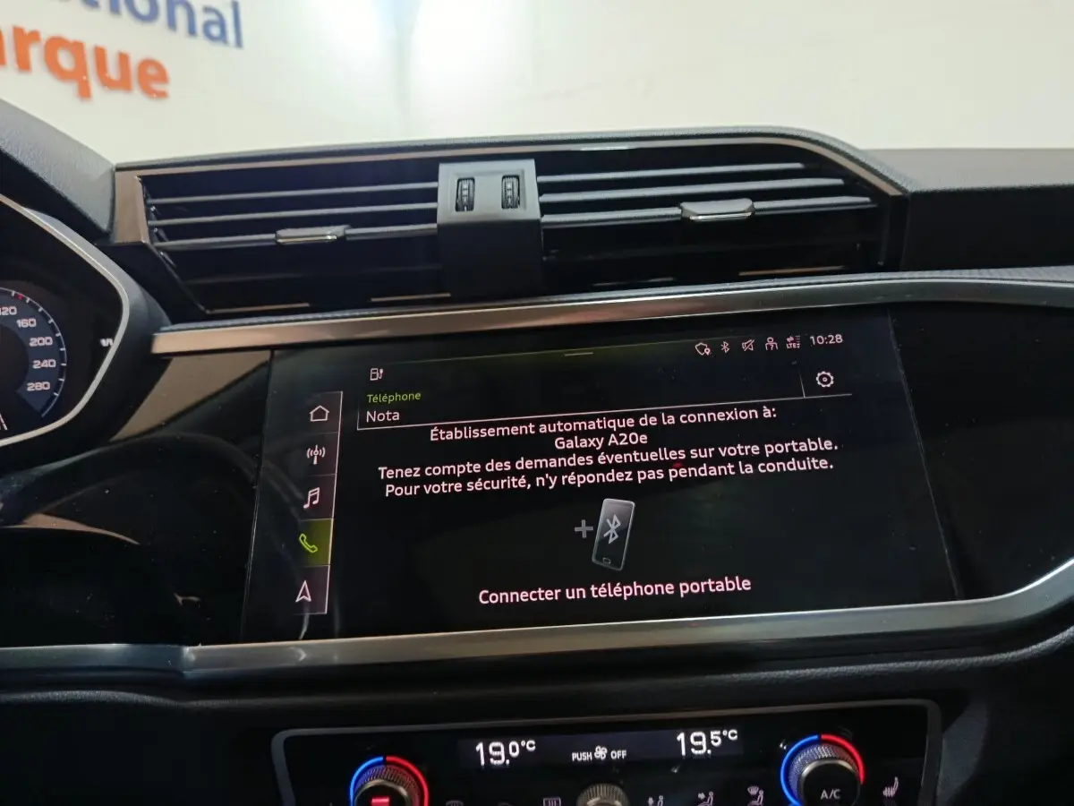 Vue rapprochée de l’écran tactile central et de la console de climatisation du tableau de bord de l’Audi Q3 Sportback gris foncé.