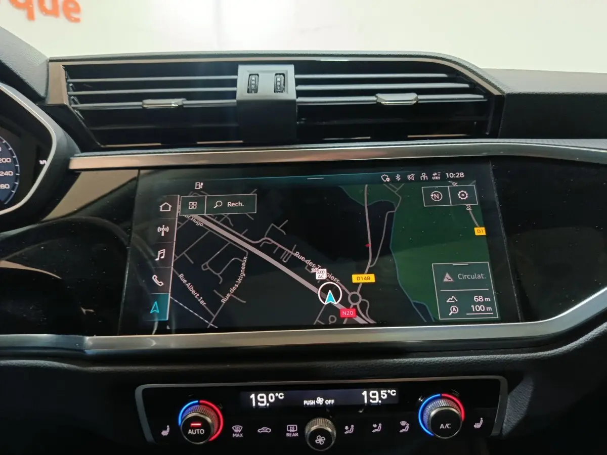 Vue rapprochée du tableau de bord de l'Audi Q3 Sportback gris foncé avec écran tactile de navigation et commandes climatisation digitales.