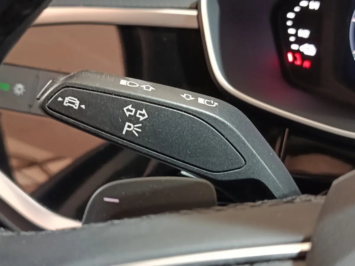 Détail du commodo de clignotant noir dans l’habitacle de l’Audi Q3 Sportback 45 TFSI e gris foncé, avec tableau de bord partiellement visible.