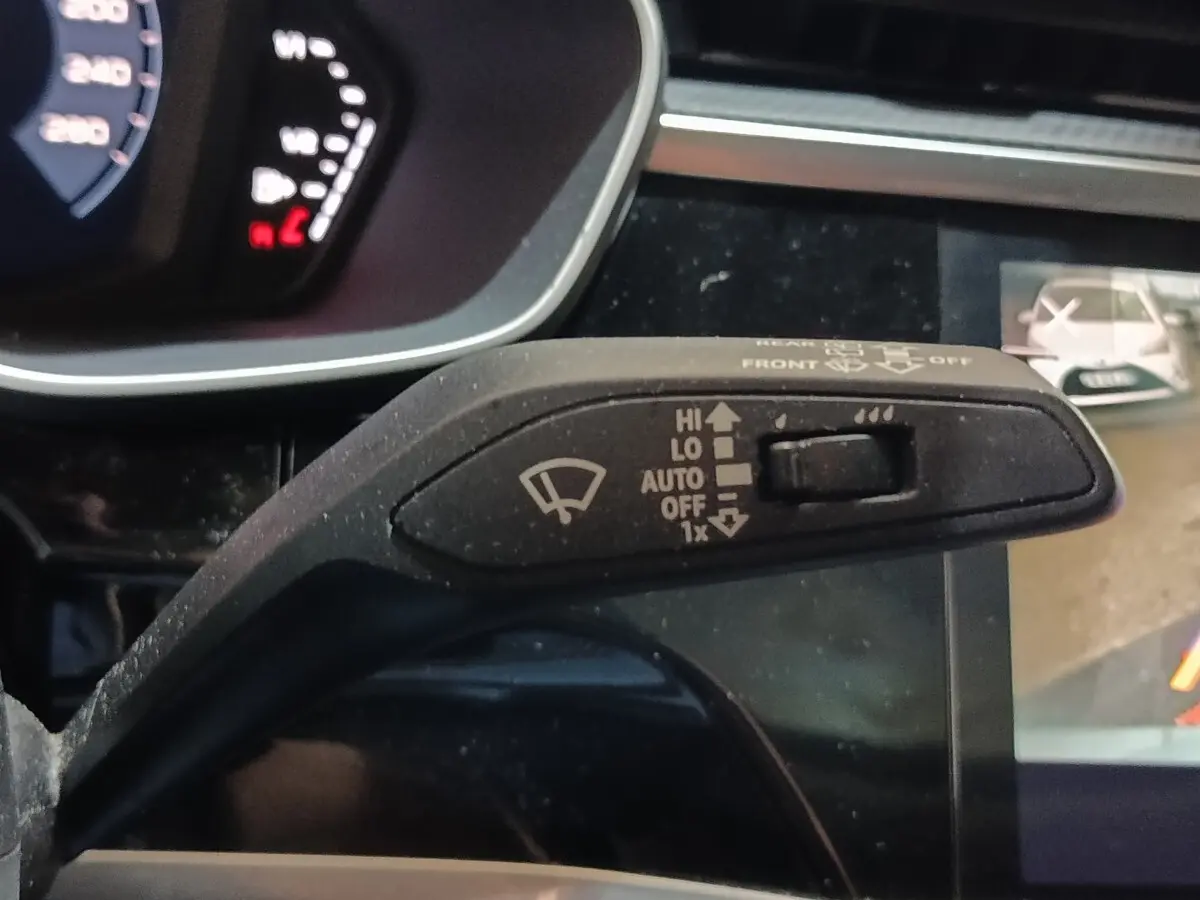 Gros plan sur la commande d’essuie-glace à gauche du volant dans l’Audi Q3 Sportback gris foncé, tableau de bord partiellement visible.