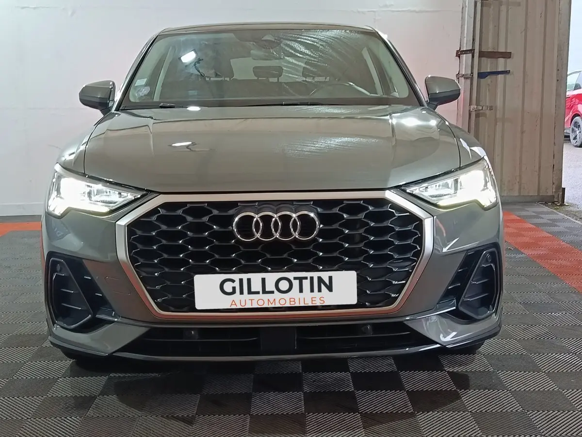 Vue avant d’un Audi Q3 Sportback gris foncé avec calandre hexagonale et phares LED allumés en intérieur.