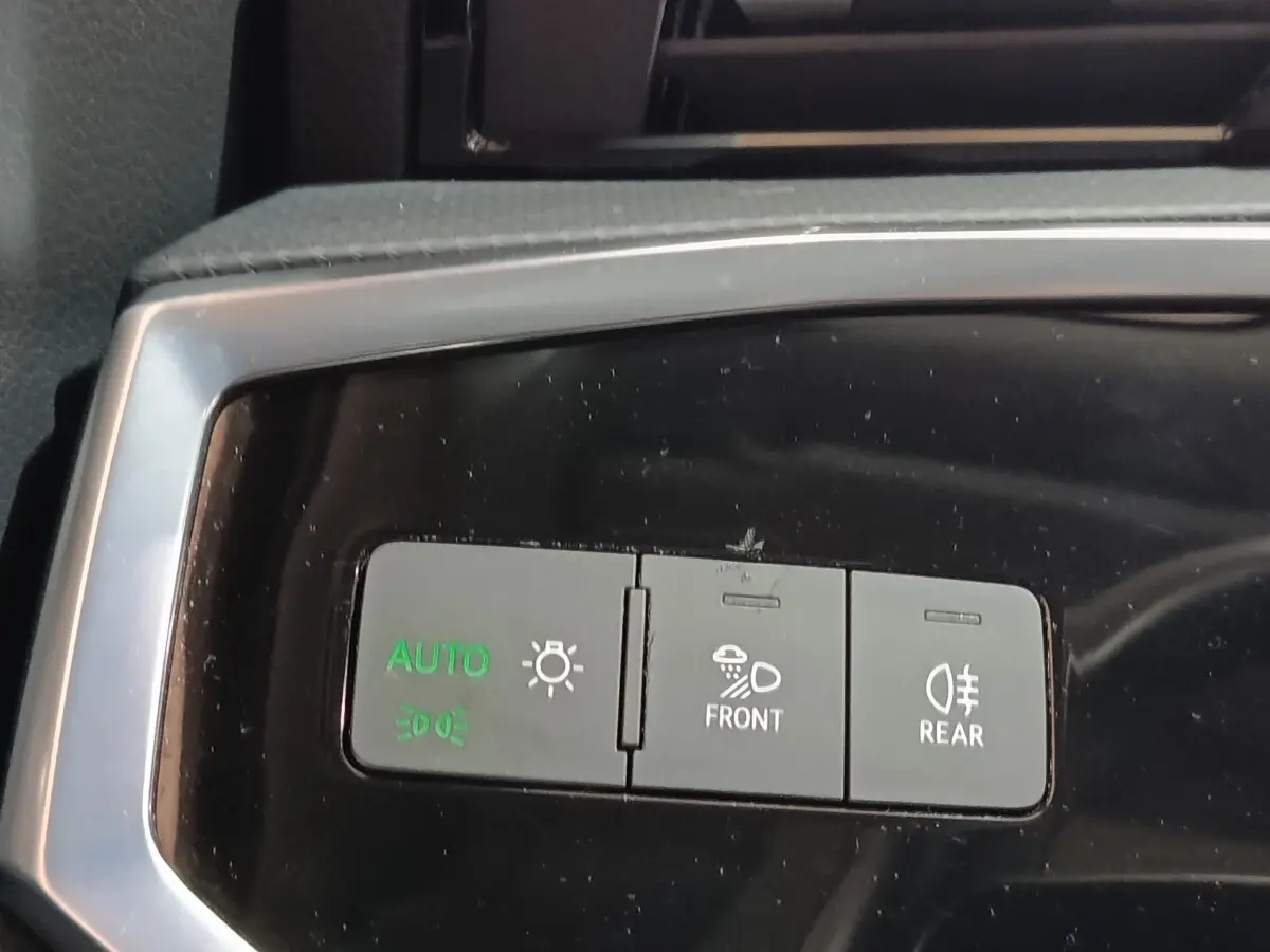 Gros plan sur les commandes d’éclairage du tableau de bord de l’Audi Q3 Sportback gris foncé, avec boutons auto, phares avant et arrière.
