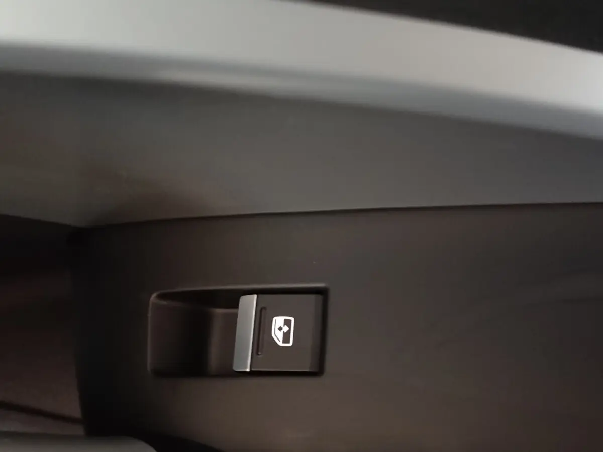 Gros plan sur le bouton de commande de la vitre électrique côté droit de l’Audi Q3 Sportback gris foncé.
