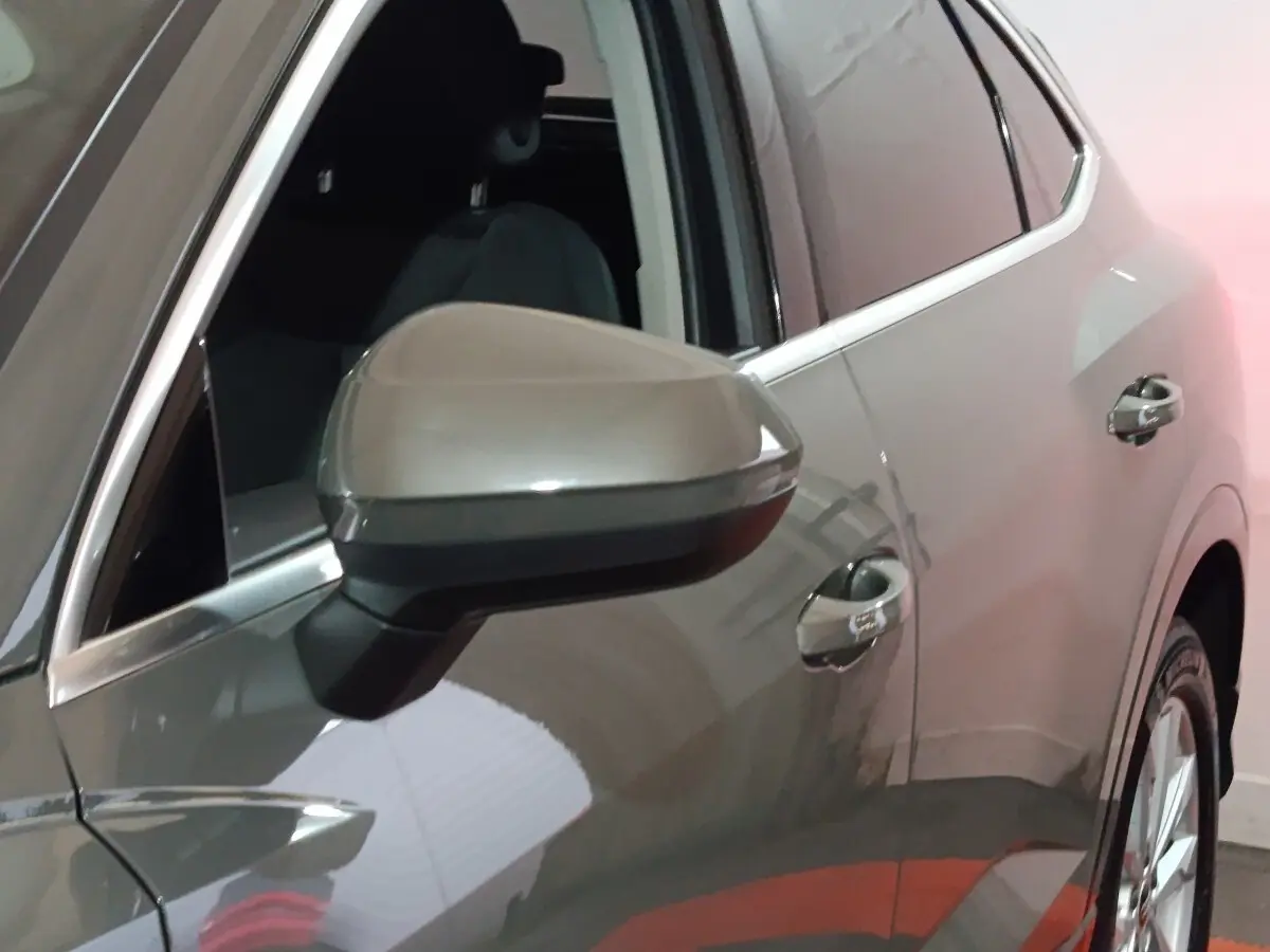 Gros plan sur le rétroviseur et la portière côté gauche d’un Audi Q3 Sportback gris foncé en intérieur.
