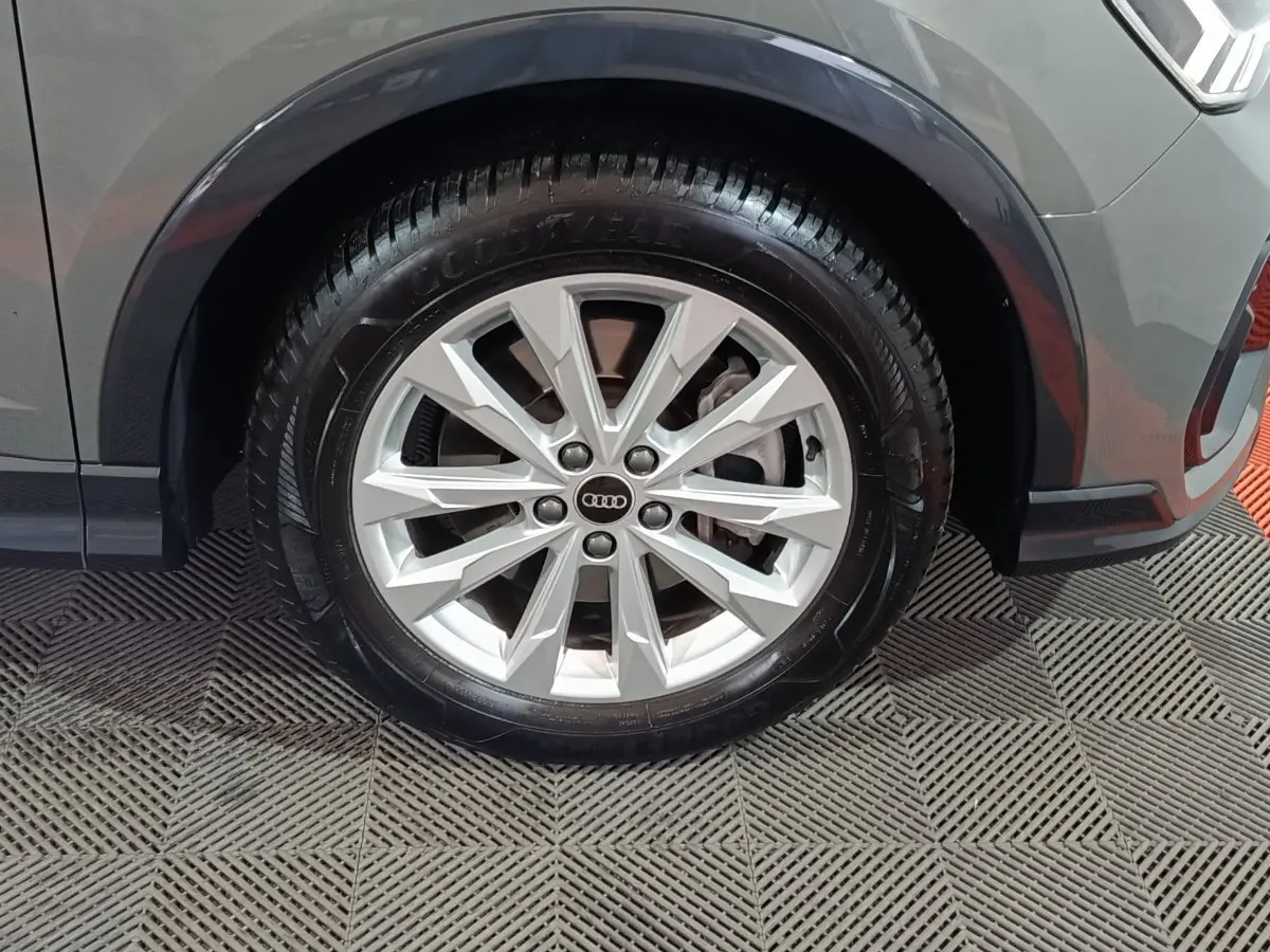 Gros plan sur la roue avant droite gris foncé de l’Audi Q3 Sportback avec jante argentée à multiples branches.