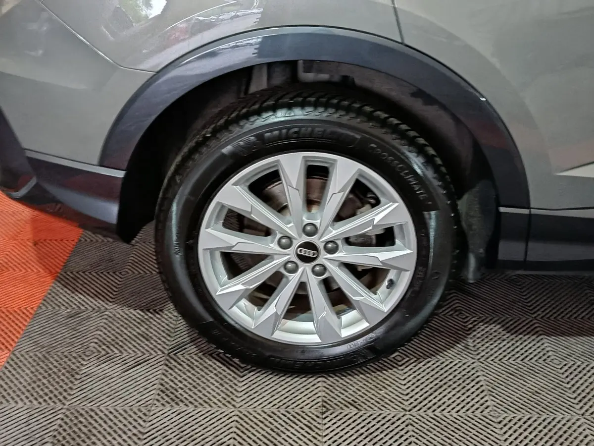 Gros plan sur la roue avant droite gris foncé d’un Audi Q3 Sportback avec jante alu à multiples branches.