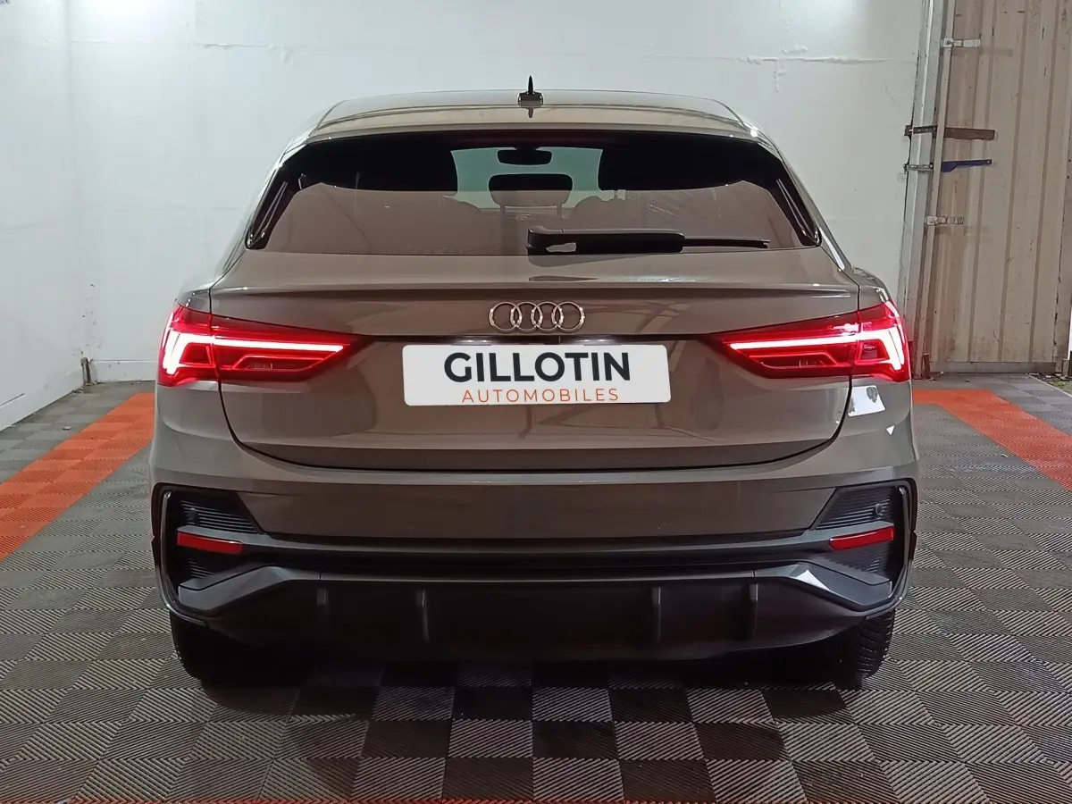 Vue arrière d'un Audi Q3 Sportback gris foncé avec feux LED allumés dans un garage.