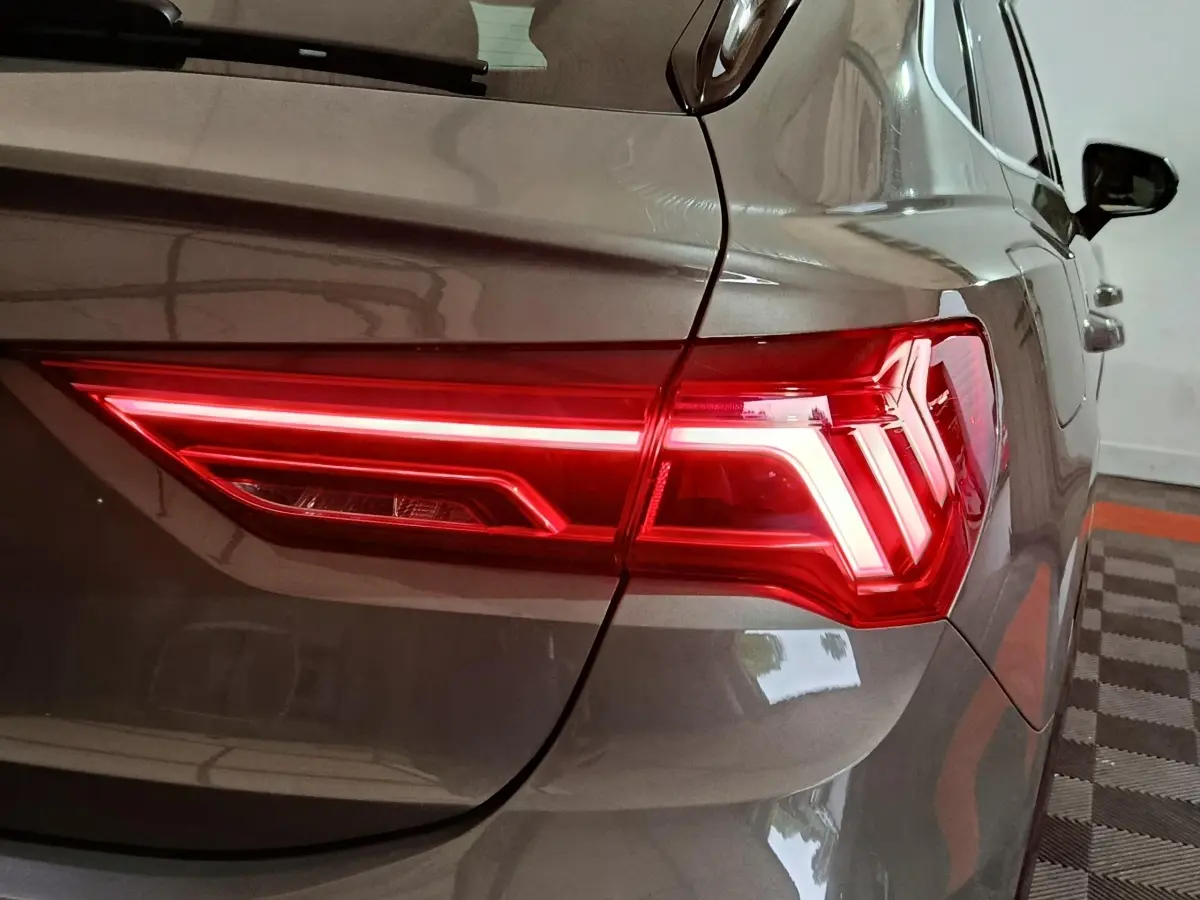 Gros plan sur le feu arrière droit allumé d’un Audi Q3 Sportback gris foncé, vue depuis l’arrière côté droit.