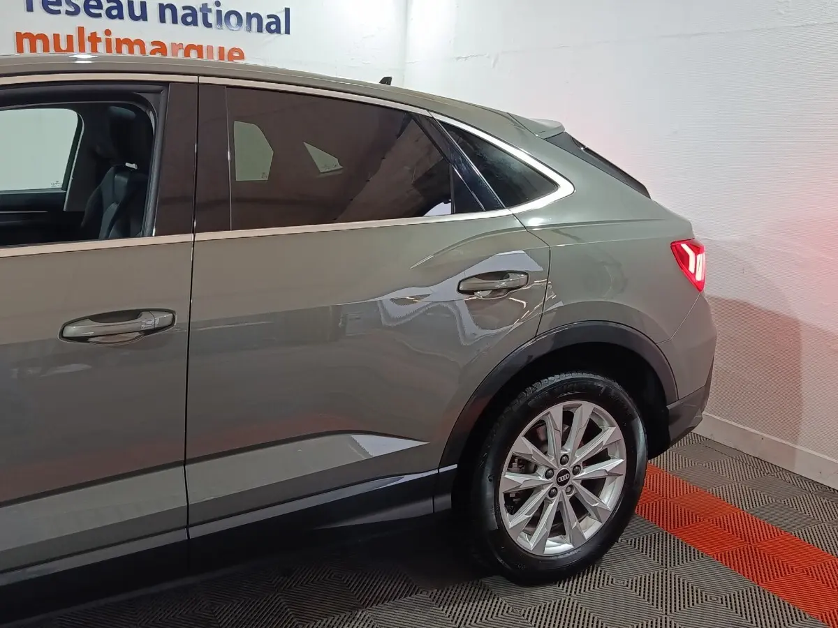 Vue latérale droite sur l’arrière d’un Audi Q3 Sportback gris foncé avec jante alliage et vitres teintées.