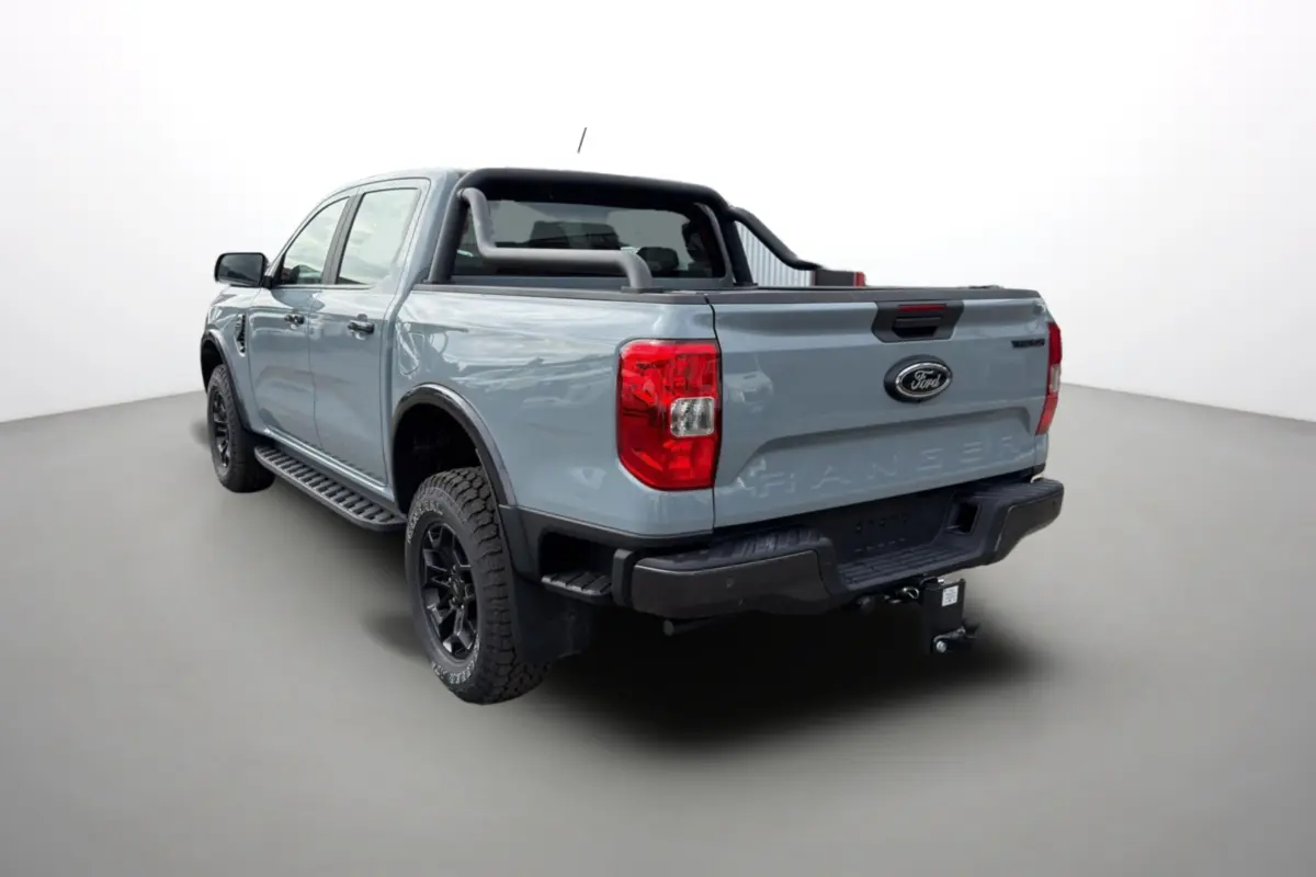 Ford Ranger gris commandeur en 3/4 arrière droit avec arceaux noirs et attelage visible sur fond neutre.