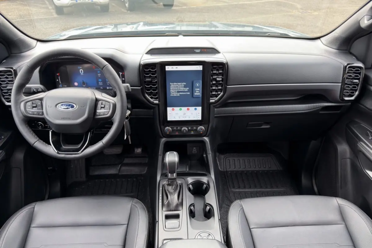 Vue intérieure avant du Ford Ranger 2026 gris, avec tableau de bord numérique et écran tactile vertical central.