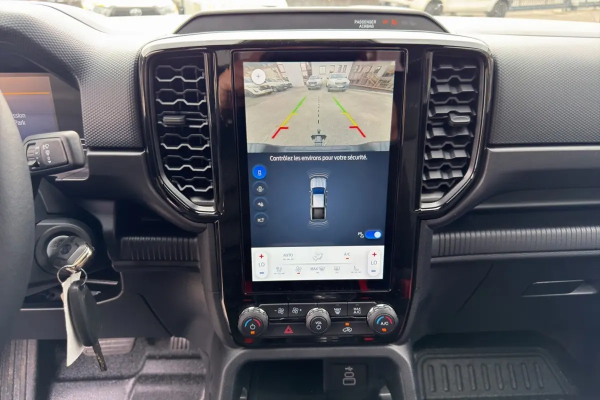 Vue rapprochée du tableau de bord noir du Ford Ranger 2026 avec écran tactile affichant la caméra de recul.