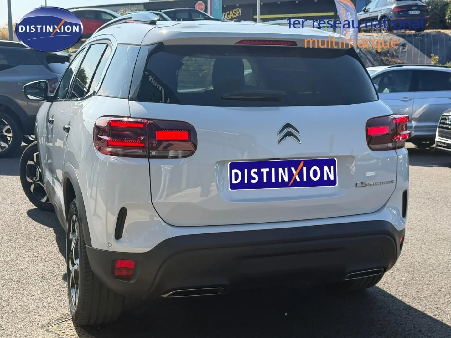 Vue 3/4 arrière du Citroën C5 Aircross blanc Okénite avec feux arrière LED et barres de toit visibles.