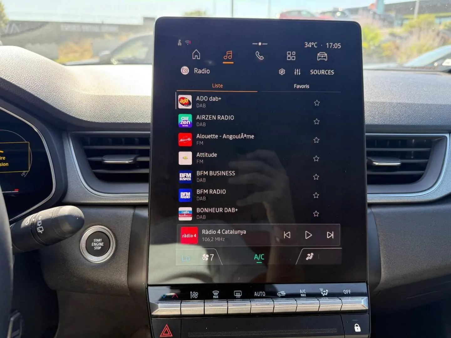 Écran tactile central du tableau de bord du Renault Captur 2025 affichant les radios DAB et commandes climatisation.