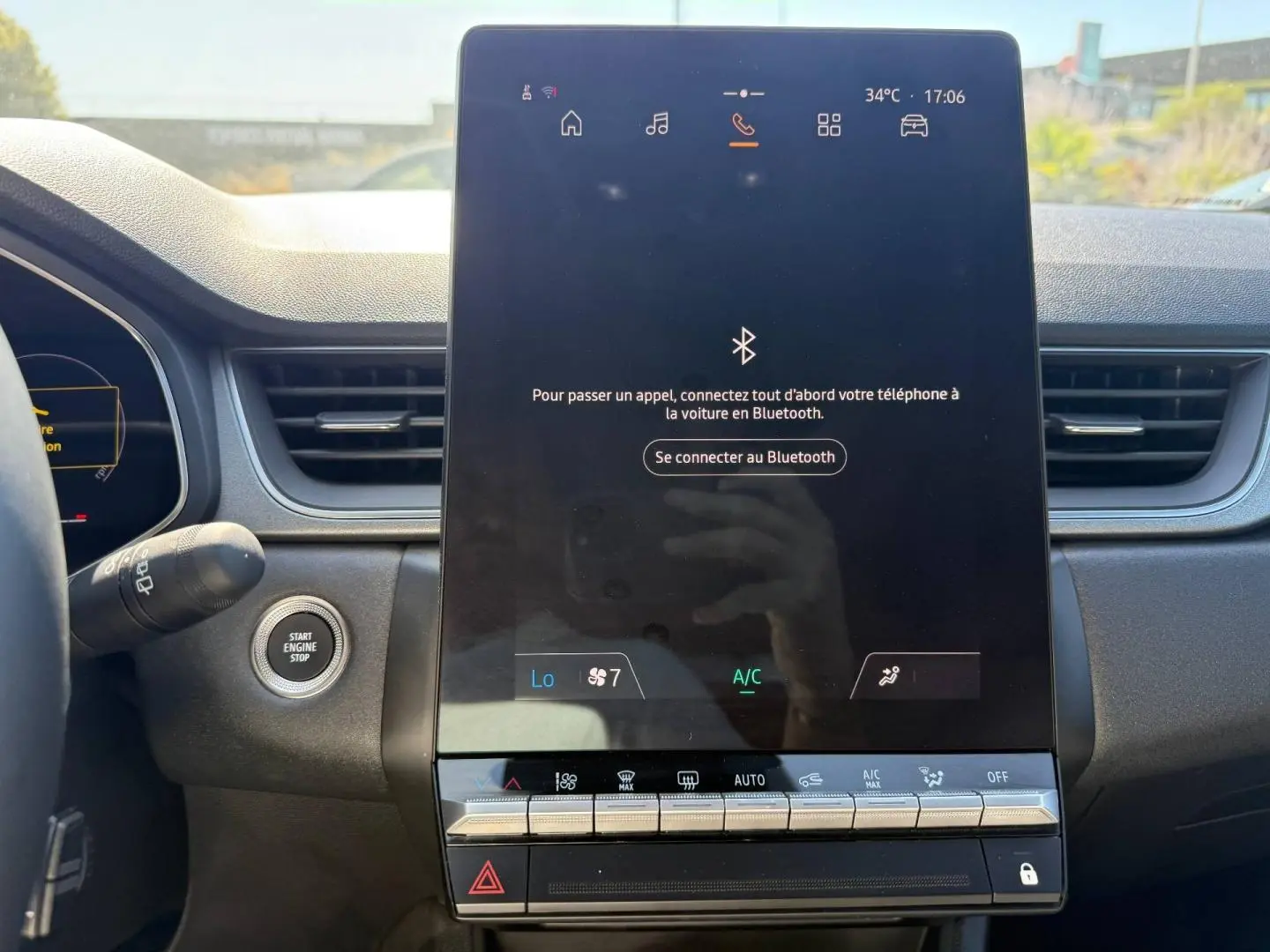 Vue intérieure centrée sur l'écran tactile vertical du tableau de bord du Renault Captur 2025, avec bouton start visible à gauche.
