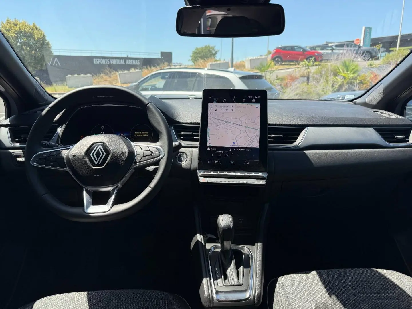 Vue intérieure avant du Renault Captur 1.6 E-Tech gris Rafale, avec volant multifonction et écran tactile central vertical.