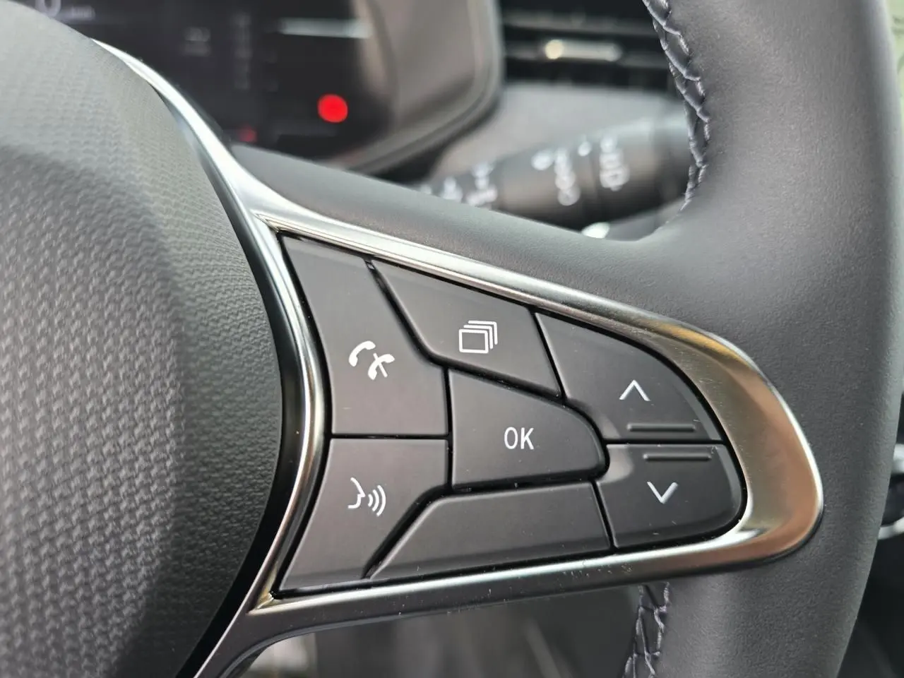 Gros plan sur les commandes multifonctions noires avec contour chromé du volant de la Renault Clio Gris Rafale Metal.