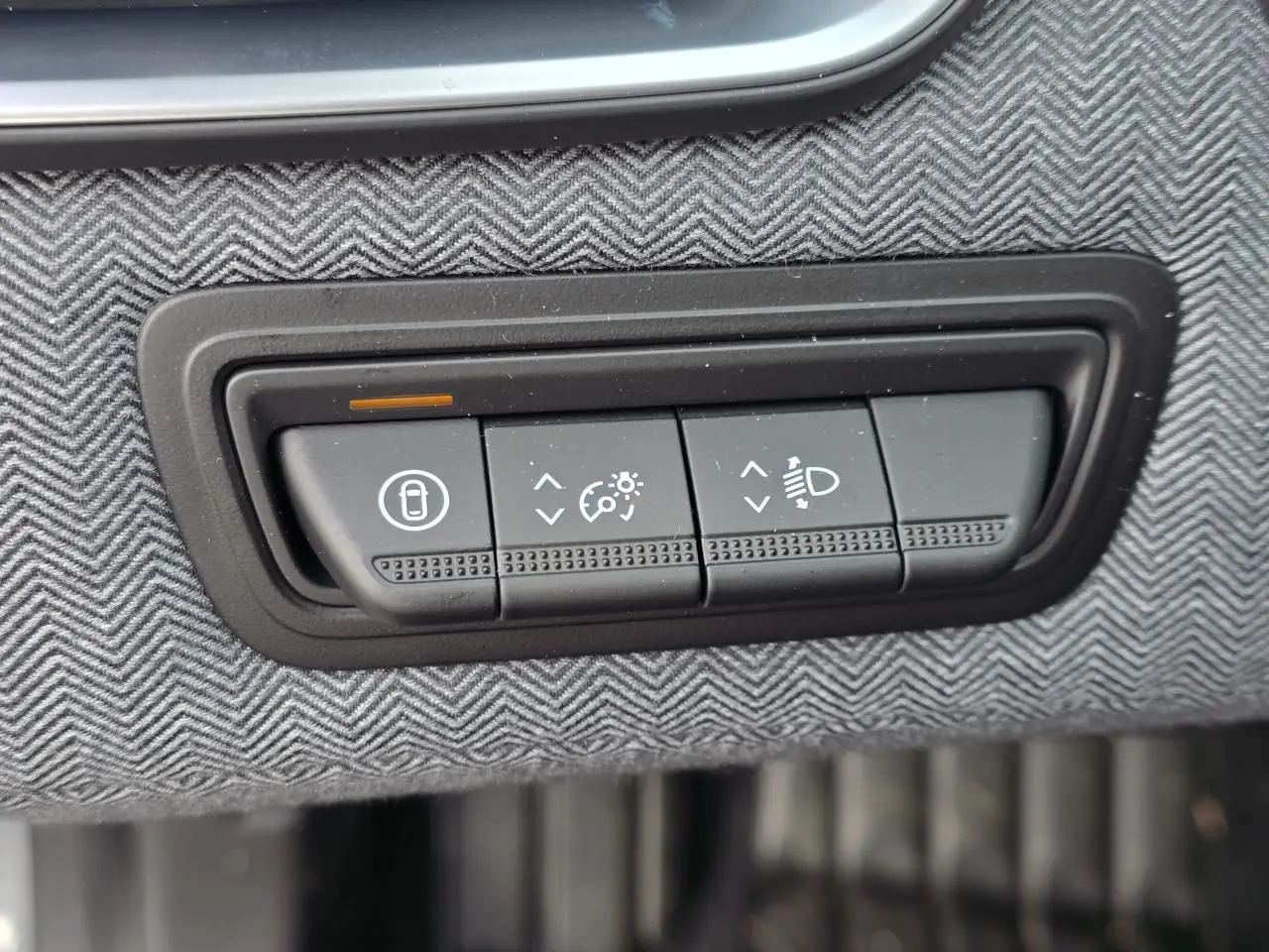 Gros plan sur les commandes d'éclairage et verrouillage sur tissu gris à chevrons dans une Renault Clio Gris Rafale Metal.