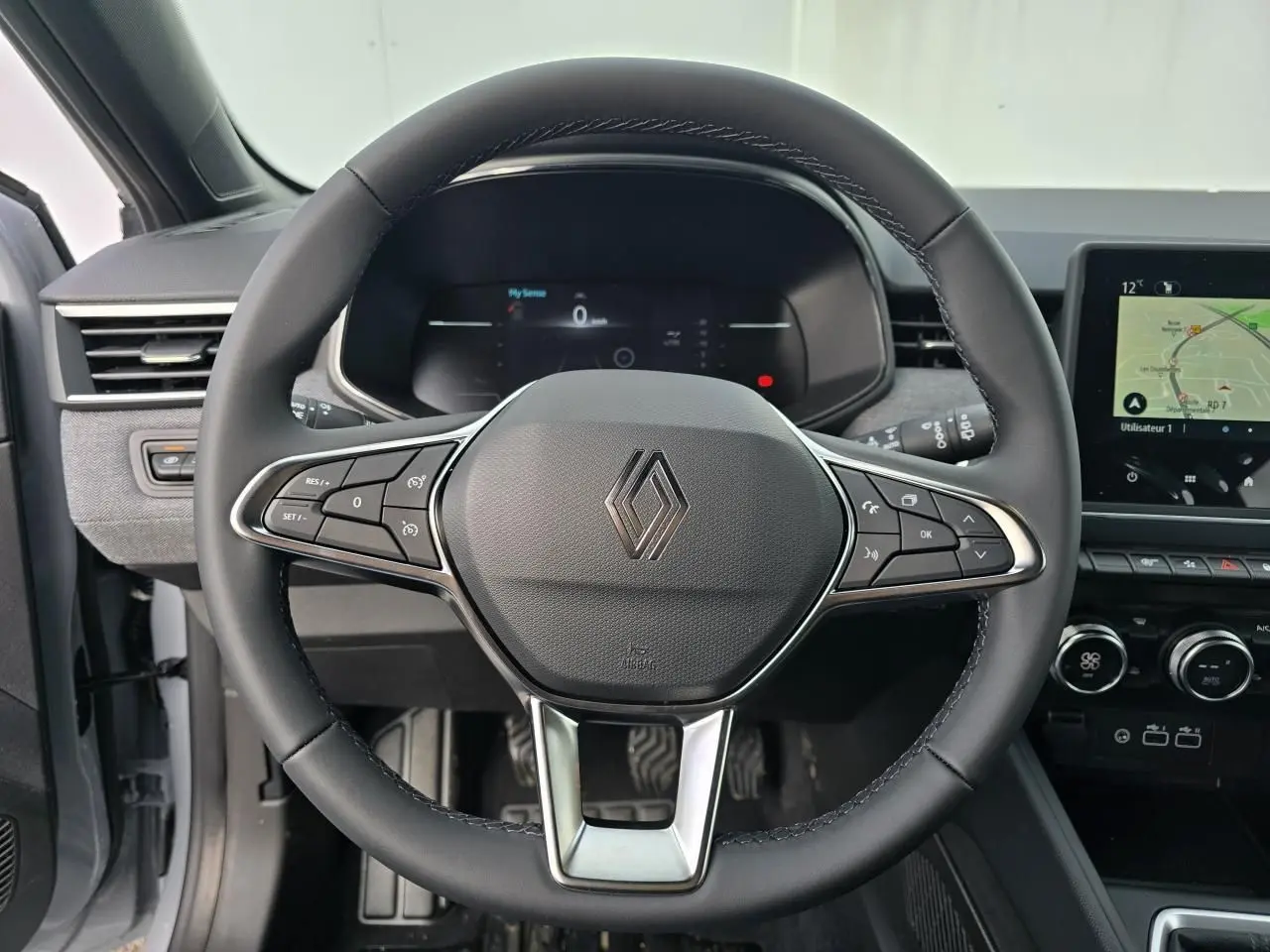 Vue centrée sur le volant multifonction noir de la Renault Clio 2025 avec tableau de bord numérique et écran tactile.