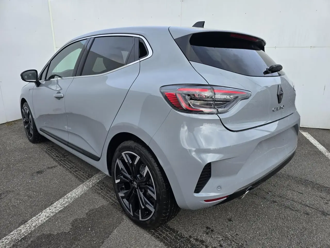 Renault Clio 2025 gris Rafale métal vue 3/4 arrière droit avec jantes alliage noires et vitres surteintées.