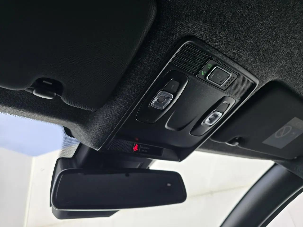 Vue intérieure du plafonnier et du rétroviseur intérieur de la Renault Clio V gris Rafale, avec commandes d’éclairage et SOS.