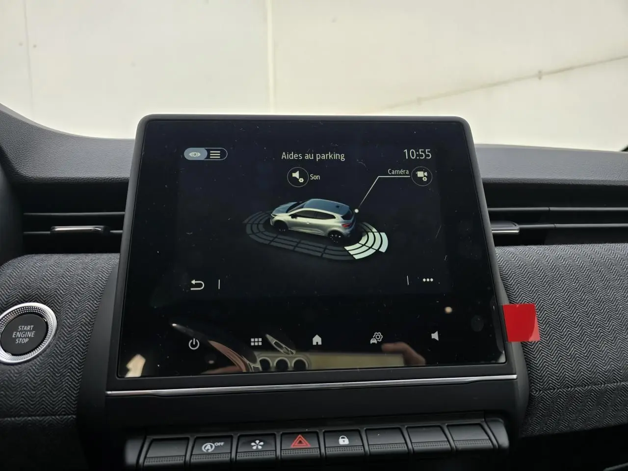 Écran tactile central affichant l'aide au stationnement de la Renault Clio V gris Rafale, vue intérieure avant.