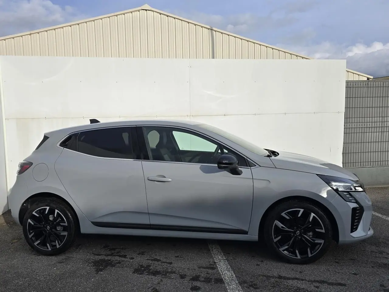 Profil côté gauche de la Renault Clio V gris Rafale métal avec jantes alliage noires et vitres surteintées.