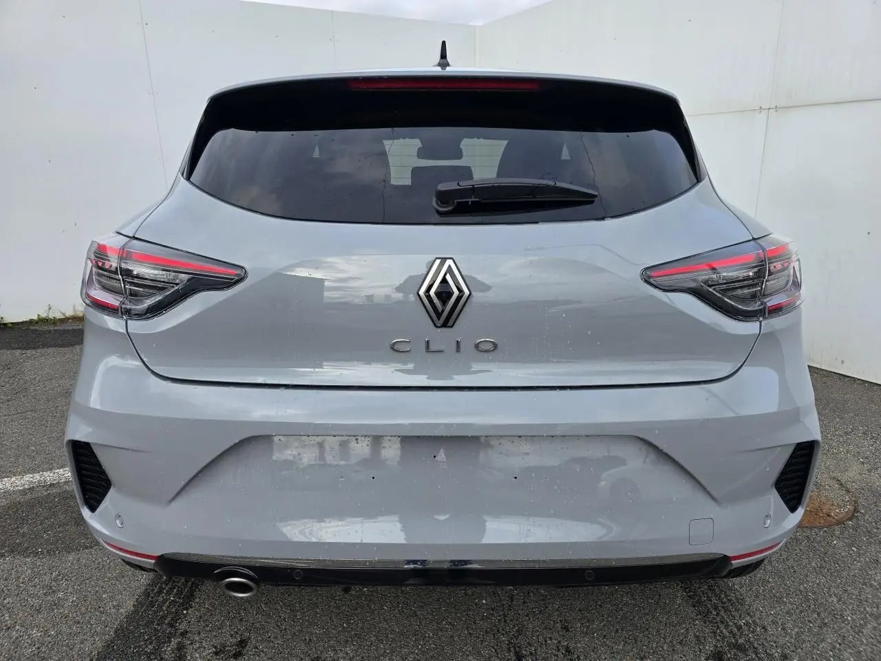 Vue arrière d'une Renault Clio gris Rafale métallisé avec feux LED en forme de C et lunette arrière surteintée.