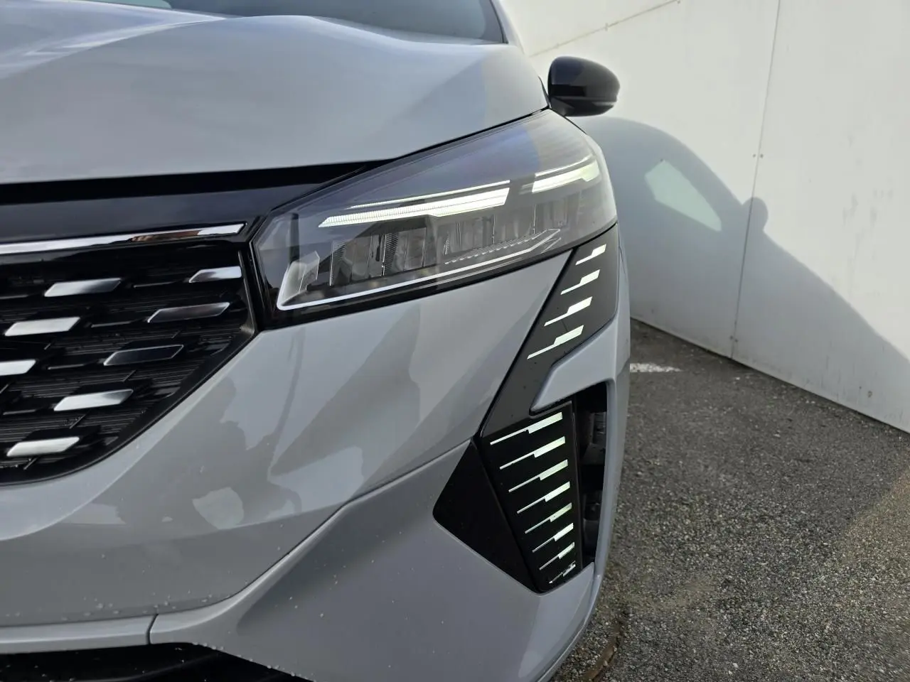 Gros plan sur l'avant droit de la Renault Clio 2025 gris Rafale Métal avec phares LED et calandre noire chromée.